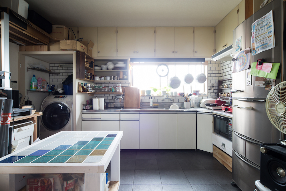 床にタイルを貼り直したキッチン。白いタイルと収納たっぷりのキッチン、洗濯機ブースはもともとのまま利用。